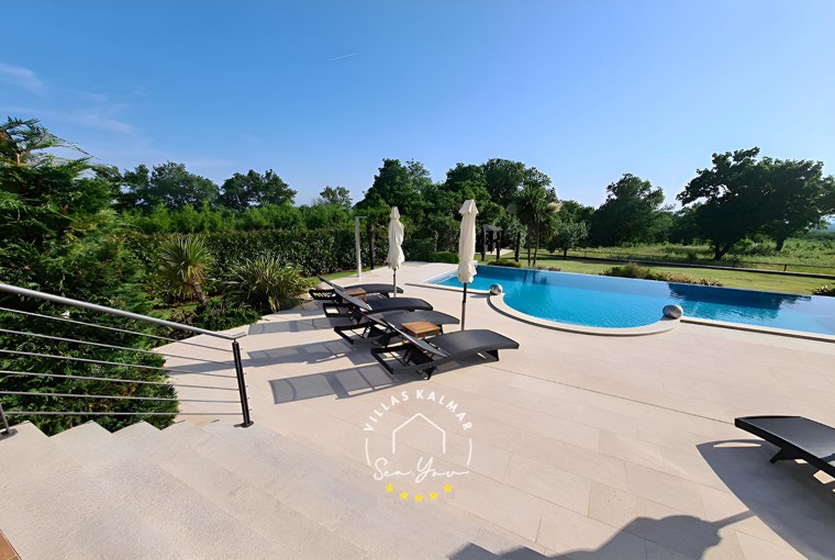 Sonnenliegen neben privatem Pool im Garten der Villa