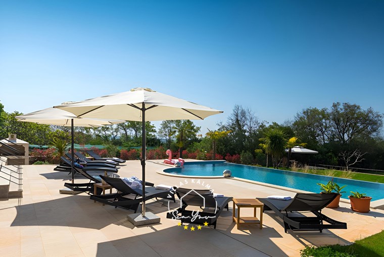 Sonnenliegen und Sonnenschirme neben dem Pool der Villa in Kastelir