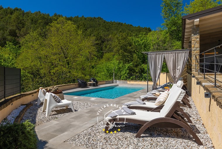 Sun loungers next to private pool of villa surrounded by nature