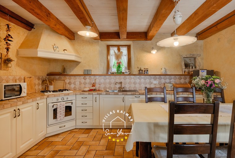 Rustikale Küche einer istrischen Villa mit Essbereich, Natursteinwänden und Holzbalkendecke