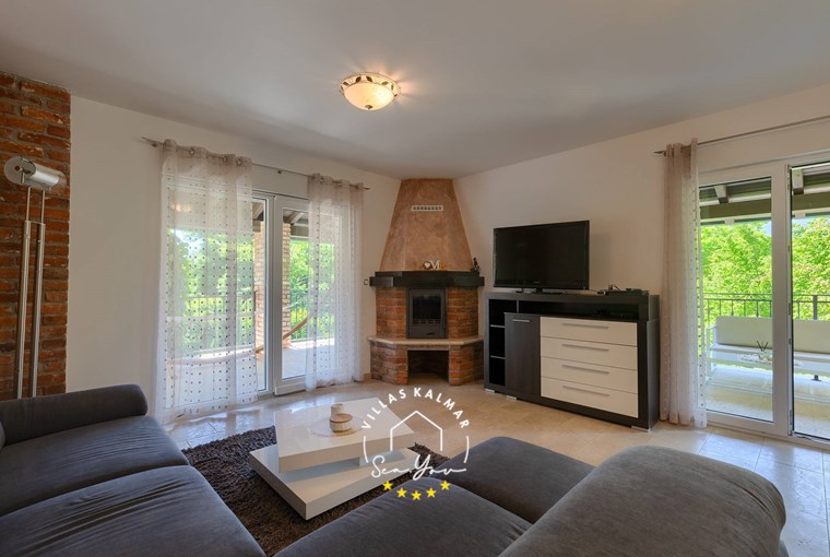 Comfortable living room with sofa, TV, fireplace and terrace access in villa near Opatija