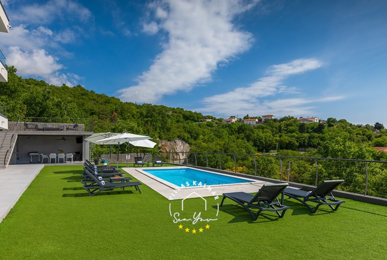 Sun loungers and parasols next to the pool with beautiful sea view in luxury Villa Lavinia in Opatija