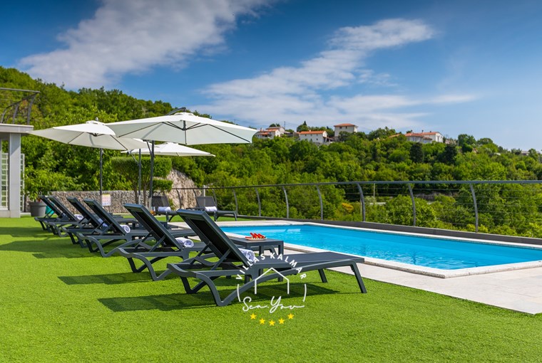 Sun loungers and parasols next to the pool with beautiful sea view in luxury Villa Lavinia in Opatija