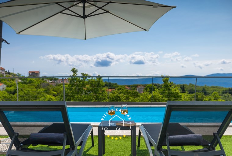 Sun loungers and parasols next to the pool with beautiful sea view in luxury Villa Lavinia in Opatija