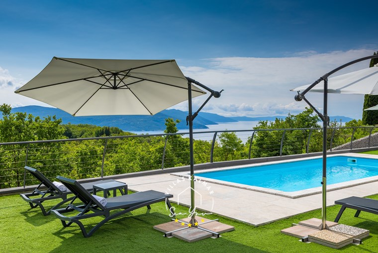 Sun loungers and parasols next to the pool with beautiful sea view in luxury Villa Lavinia in Opatija