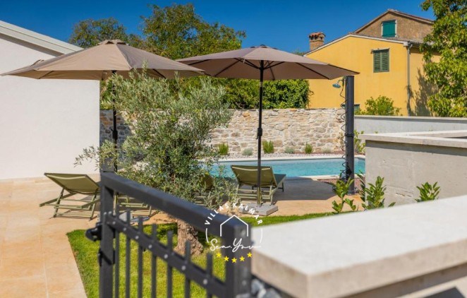 Outdoor area of Villa Andrea with garden, private pool and sun loungers with parasols