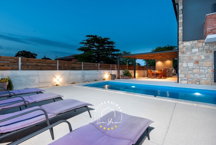 Sun loungers next to the pool and covered outdoor dining area in Villa Baraka