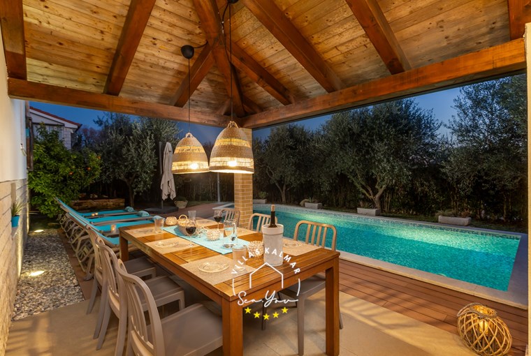 Outdoor dining table next to the private pool of the villa at night