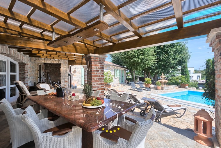 Vanjski stol za blagovanje s pogledom na bazen u vili